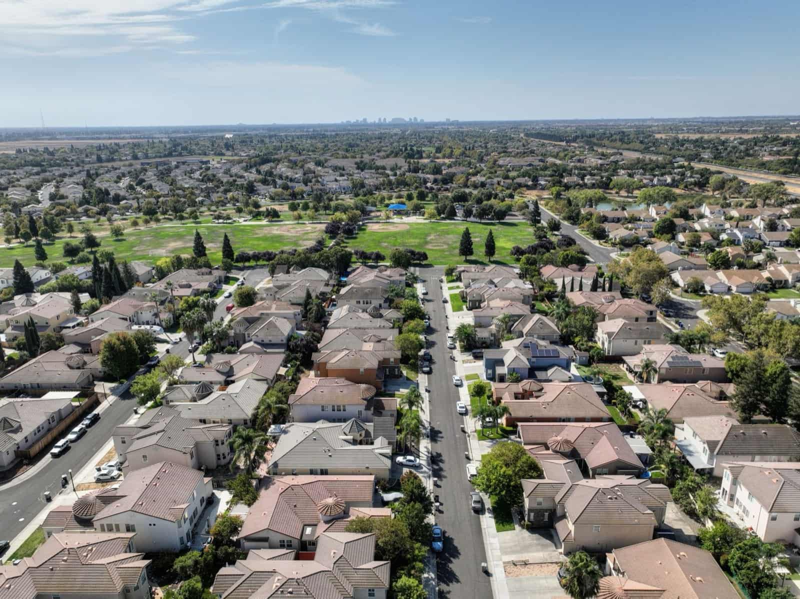 Aerial view of a Sun Belt residential neighborhood with tile-roofed homes and a park