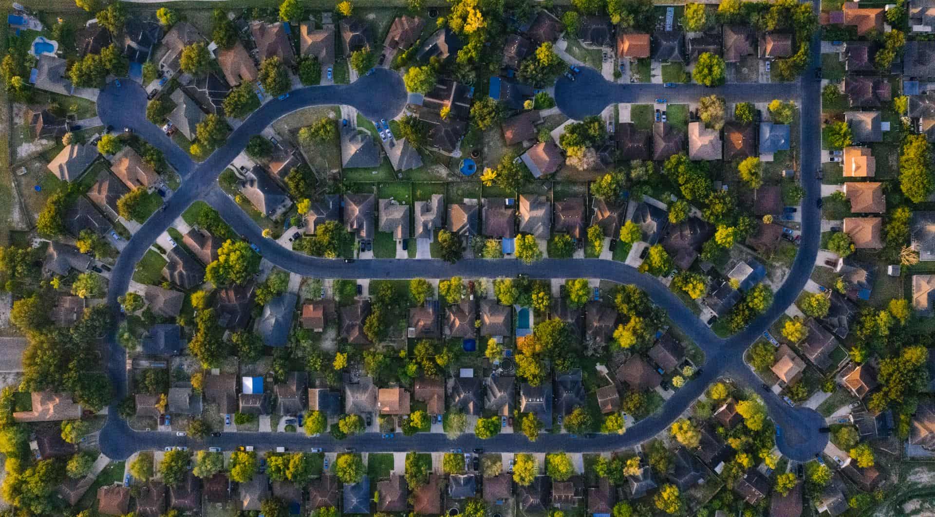 Overhead view of a residential subdivision, its curving streets lined with mature shade trees