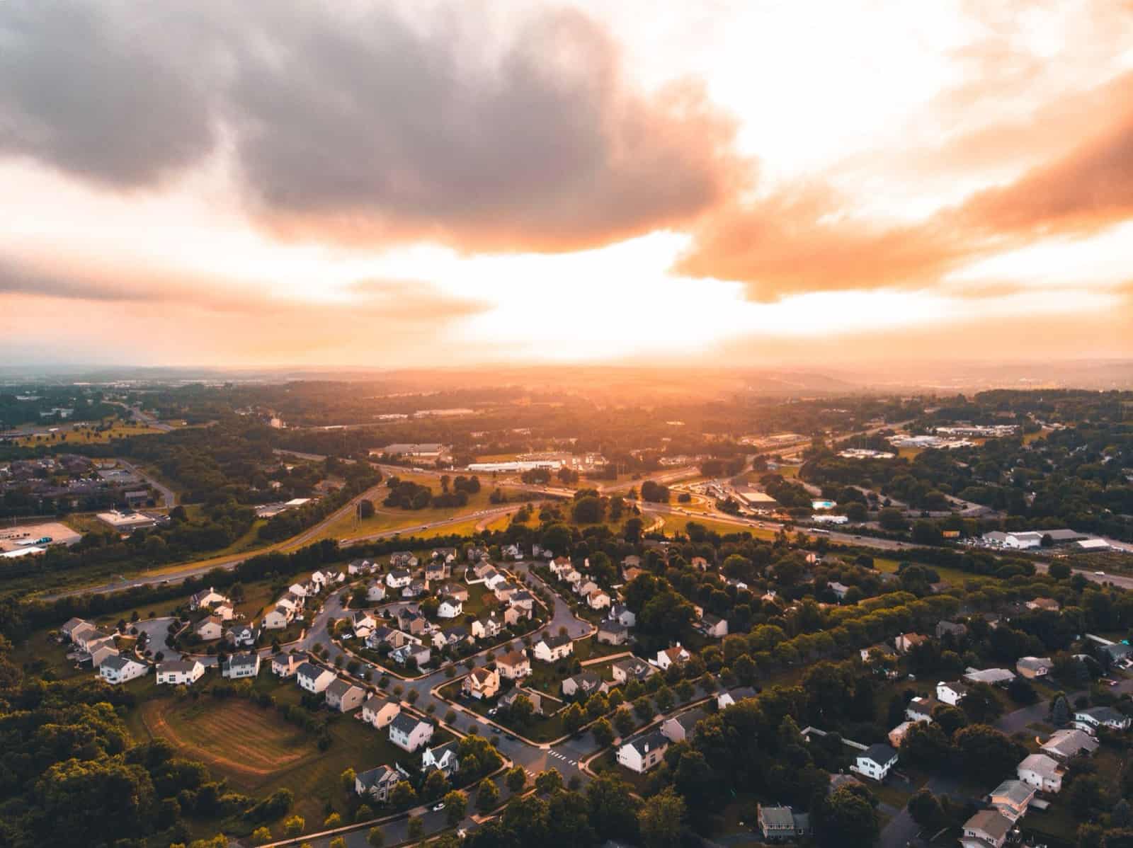 Aerial view of a residential neighborhood at sunset with dramatic clouds