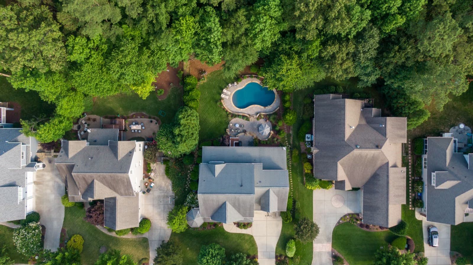 Aerial view of upscale homes with pools set among mature trees