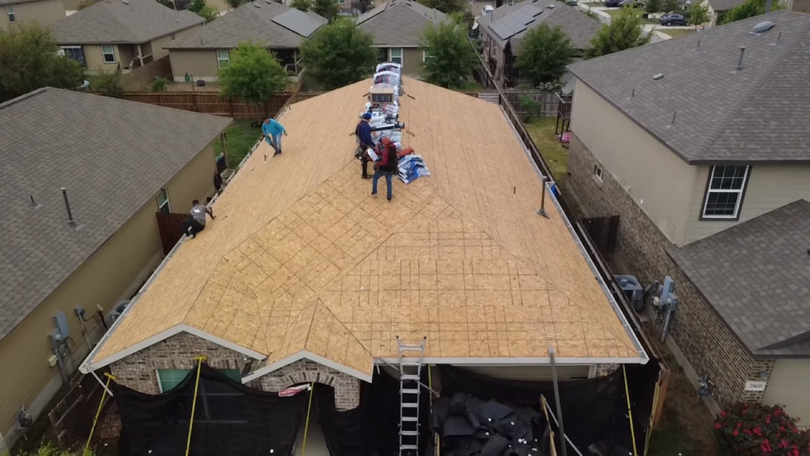 Crew installing a new roof over fresh decking, seen from above