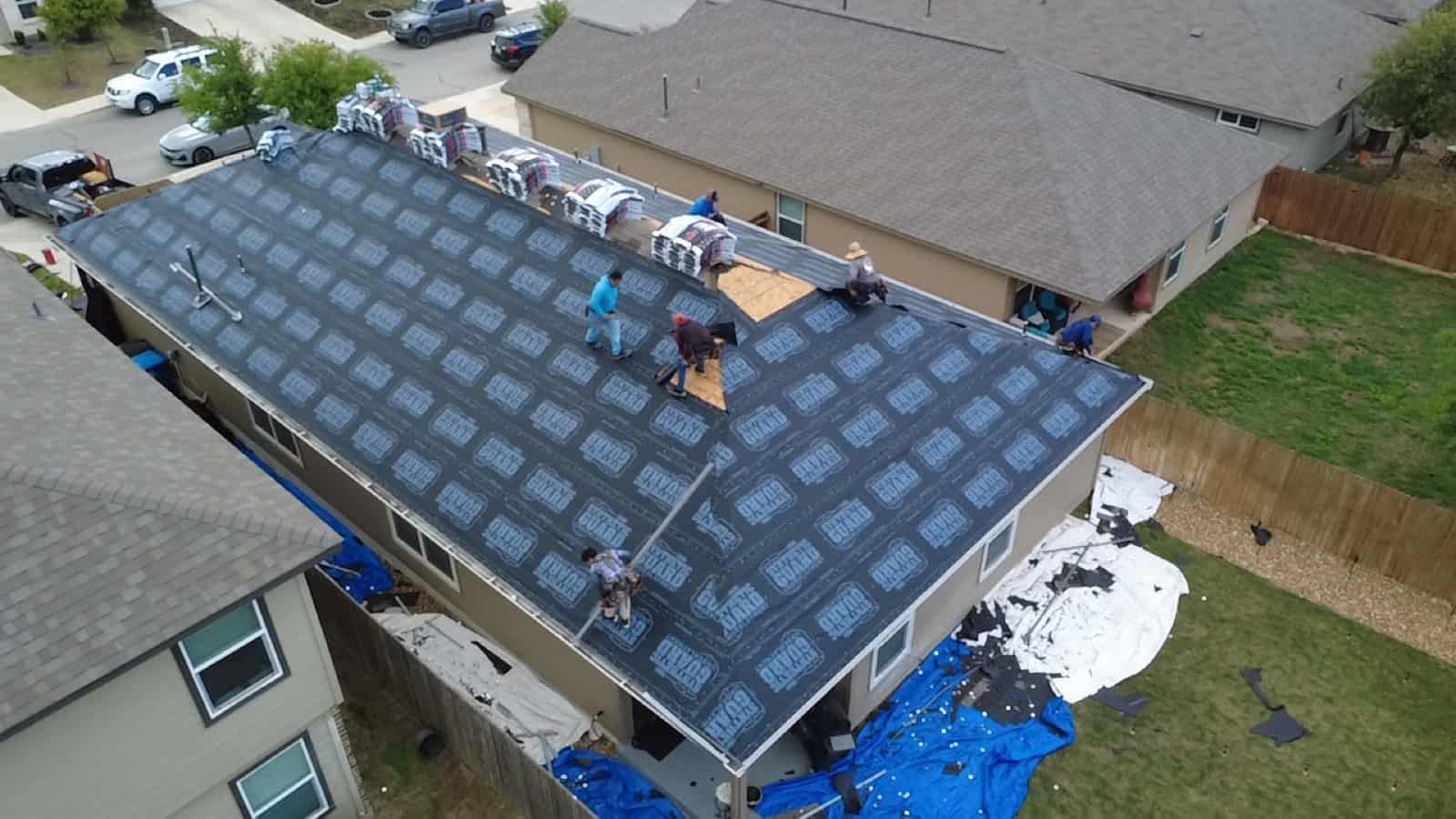 Roofing crew replacing a roof in San Antonio, synthetic underlayment down across the deck