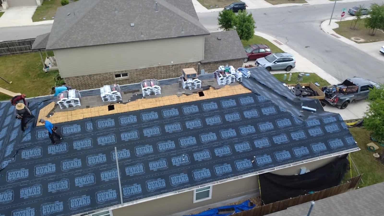 Roof replacement in progress with underlayment down across a large home