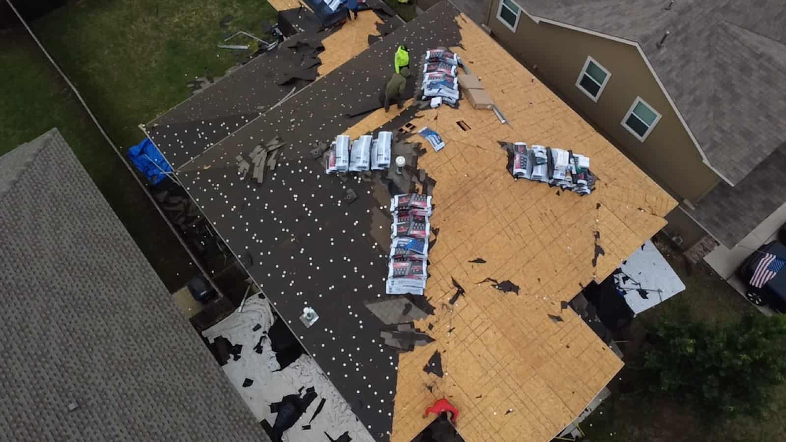 Roofing crew working across a roof during a full replacement, seen from above