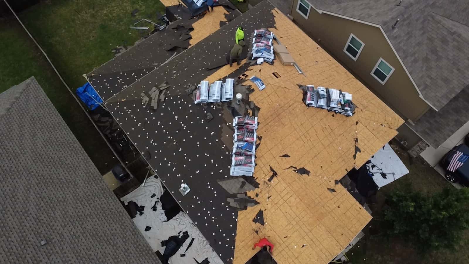 Roofing crew working across a roof during a full replacement, seen from above