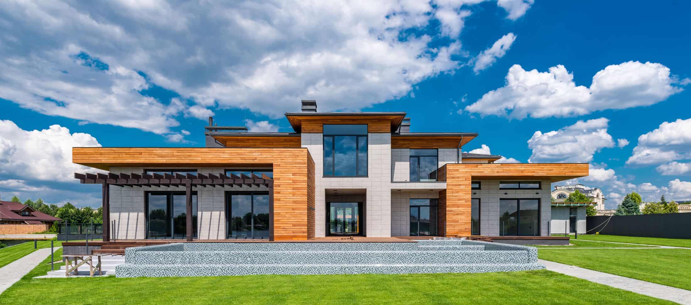 Modern two-story home with flat rooflines, wood and stone cladding, and a wide lawn
